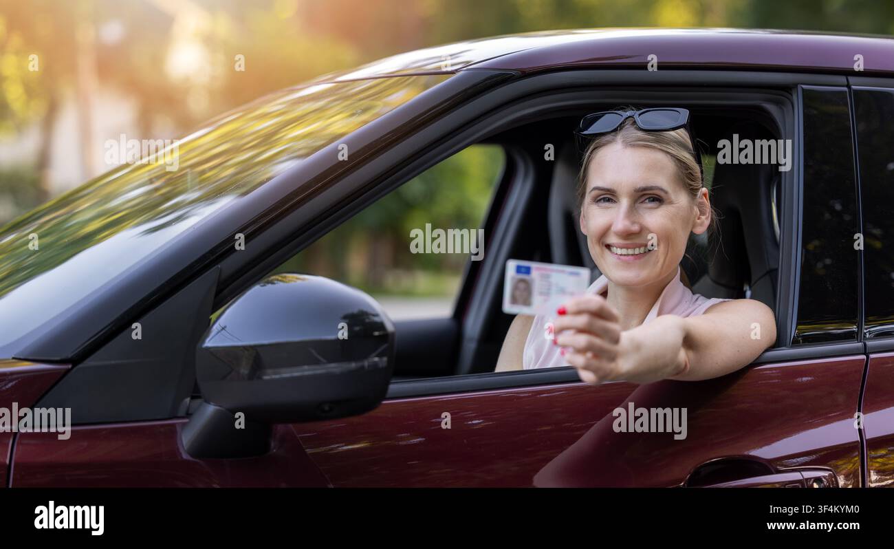 Donna felice che mostra la patente dal finestrino dell'auto dopo aver superato l'esame di guida. Banner con spazio per il testo Foto Stock