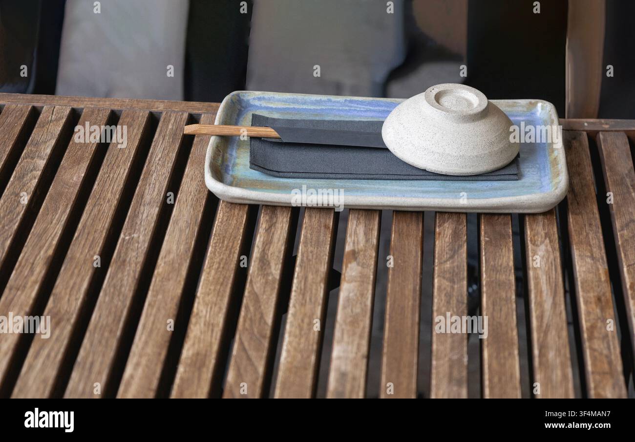 Ciotola di ceramica moderna e bacchette su un tavolo di legno in un ristorante Foto Stock