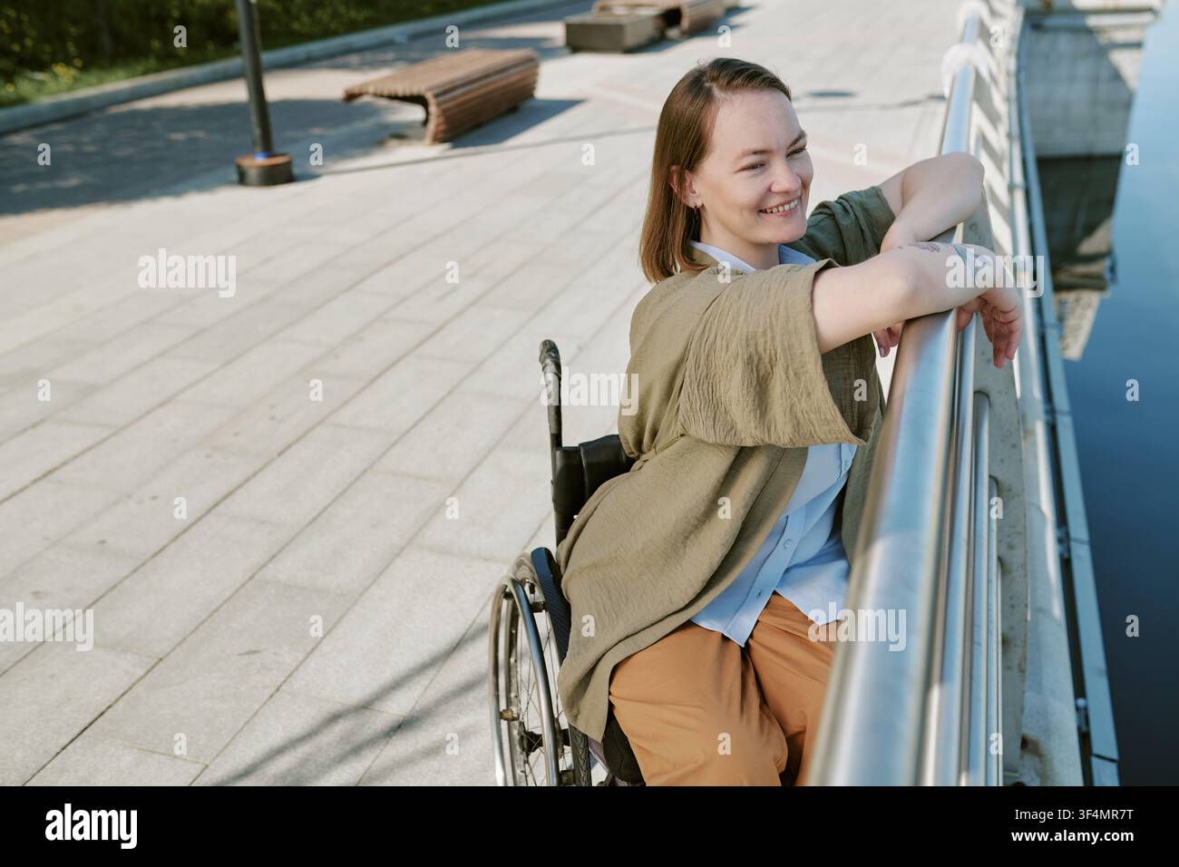 Giovane donna adulta con disabilità che si gode una pausa in riva al fiume all'aperto Foto Stock