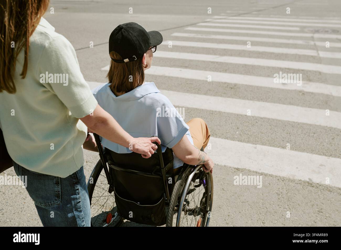 Donna con disabilità che attraversa la strada con un'assistente femminile Foto Stock