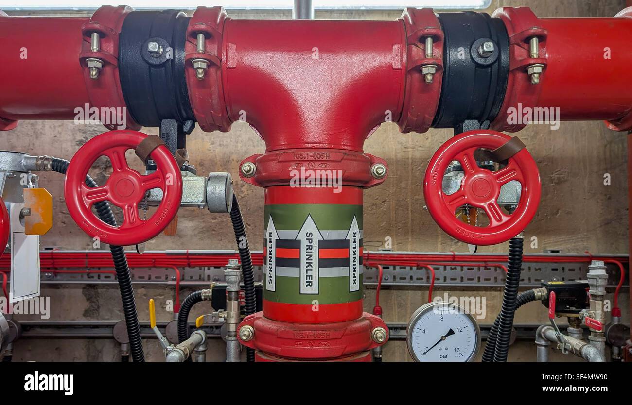Tubature per sprinkler antincendio con valvole di intercettazione, manometro e collettore di distribuzione installati in un sistema di protezione antincendio commerciale. Foto Stock
