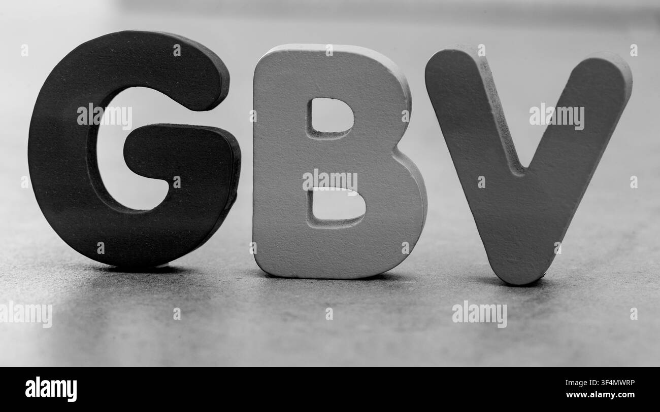 Blocchi alfabetici di legno che compongono GBV in nero, bianco e grigio su uno sfondo neutro. Immagine concettuale che rappresenta la violenza basata sul genere, domest Foto Stock