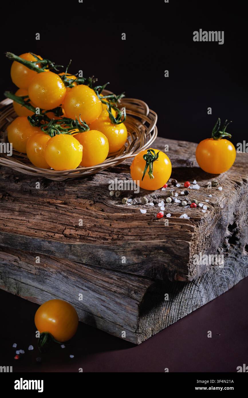 Pomodorini gialli freschi su legno con grani di sale e pepe Foto Stock
