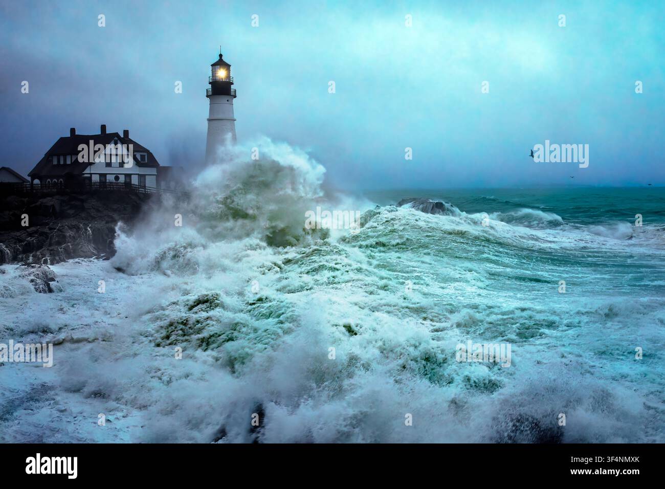 Le onde si abbattono contro il faro di Portland Head mentre una tempesta del nord-est colpisce la costa del Maine in un giorno di dicembre. Foto Stock