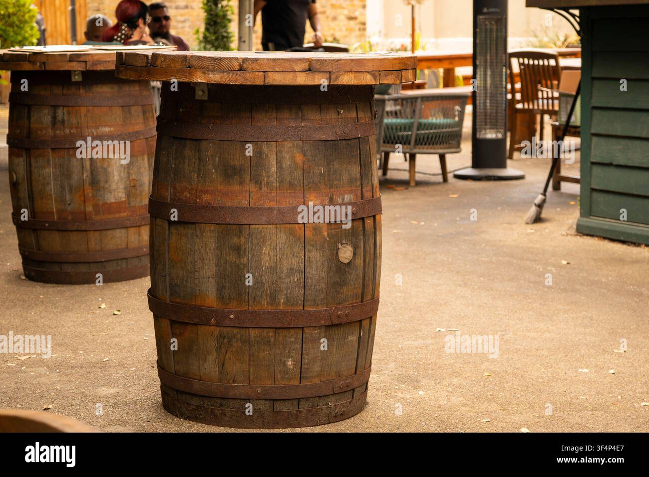 Barile di legno rustico usato come tavolo da appoggio in un giardino di un pub all'aperto. Foto Stock