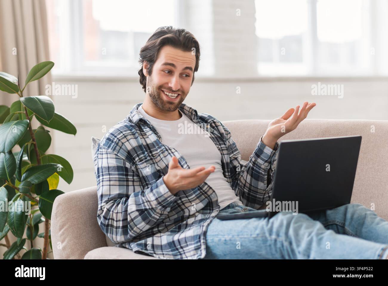 Uomo caucasico sorridente che lavora su un laptop, si rilassa a casa, concetto aziendale Foto Stock