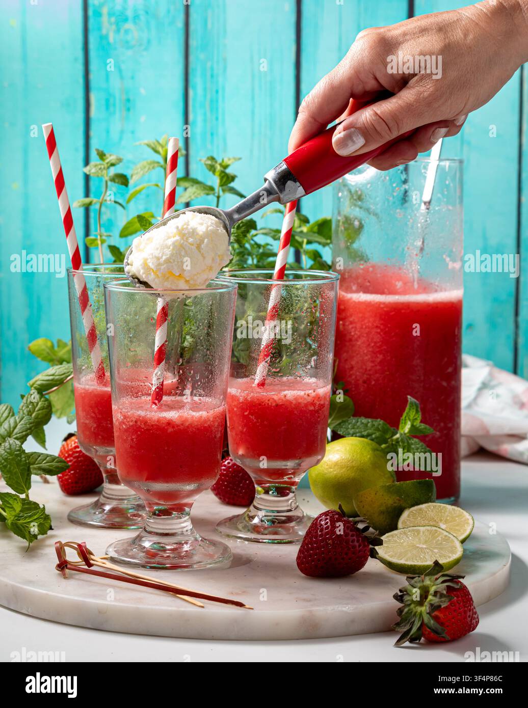 Bicchieri di daiquiri alla fragola appena versato con gelato alla vaniglia aggiunto Foto Stock