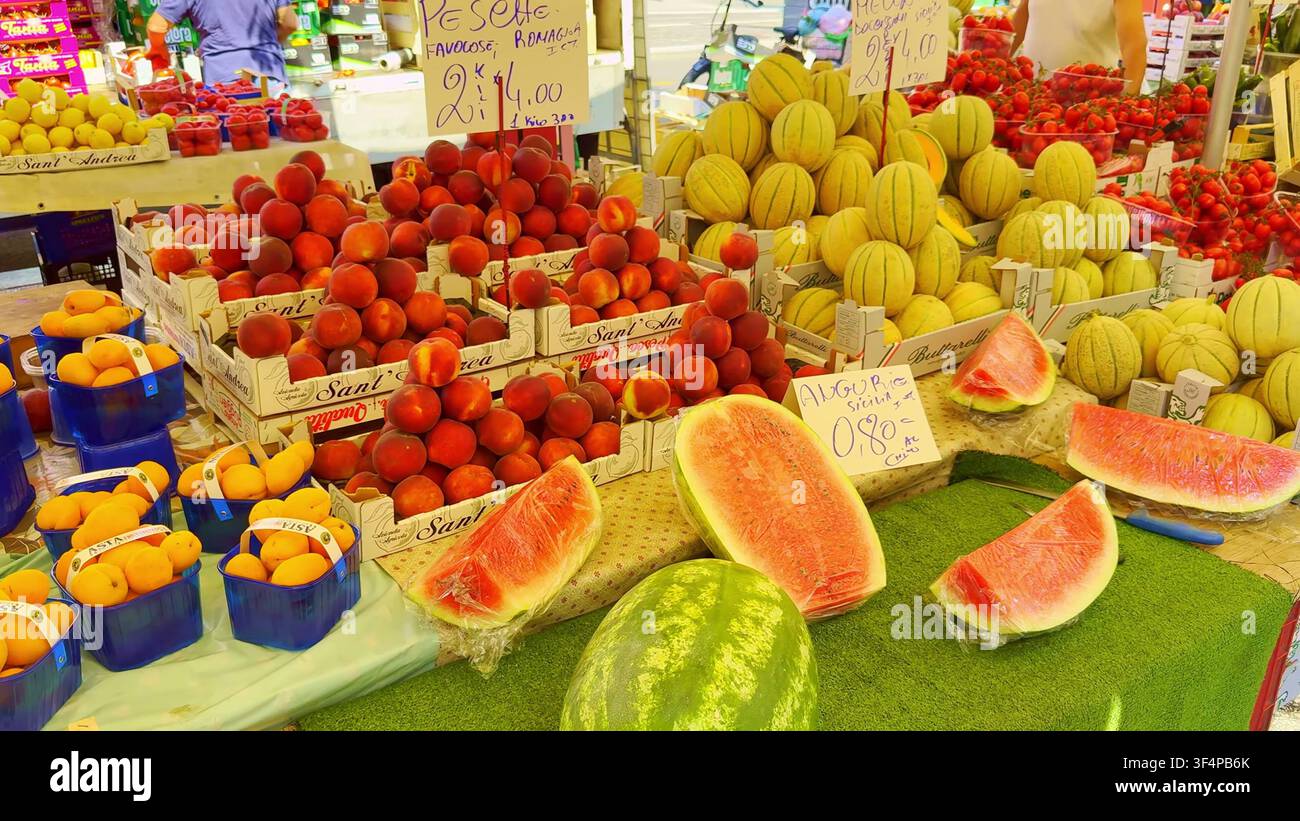 MILANO, ITALIA - 15 GIUGNO 2024: Una colorata esposizione di pesche fresche, angurie affettate, meloni e albicocche in un banco di mercato all'aperto a Milano Foto Stock