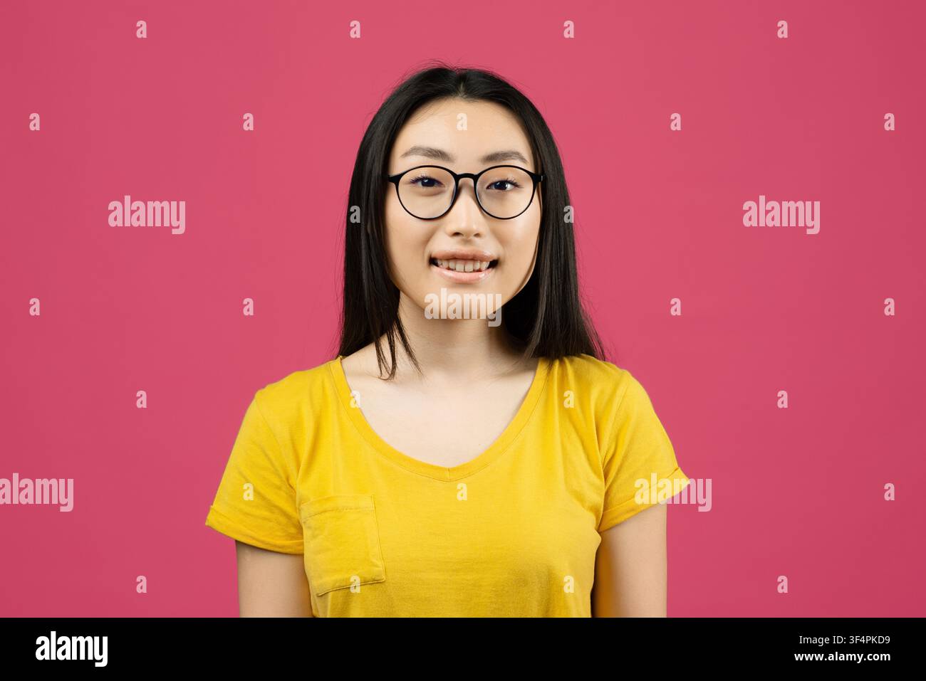 Donna asiatica sorridente con occhiali su sfondo rosa Foto Stock