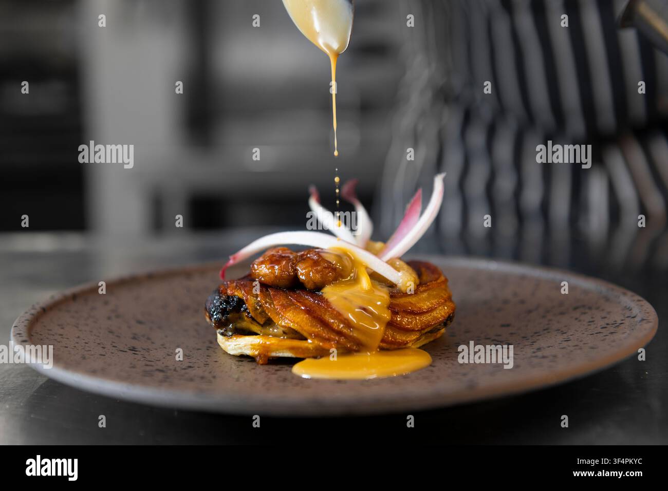 Creazione delicata di dessert in una cucina culinaria affollata Foto Stock