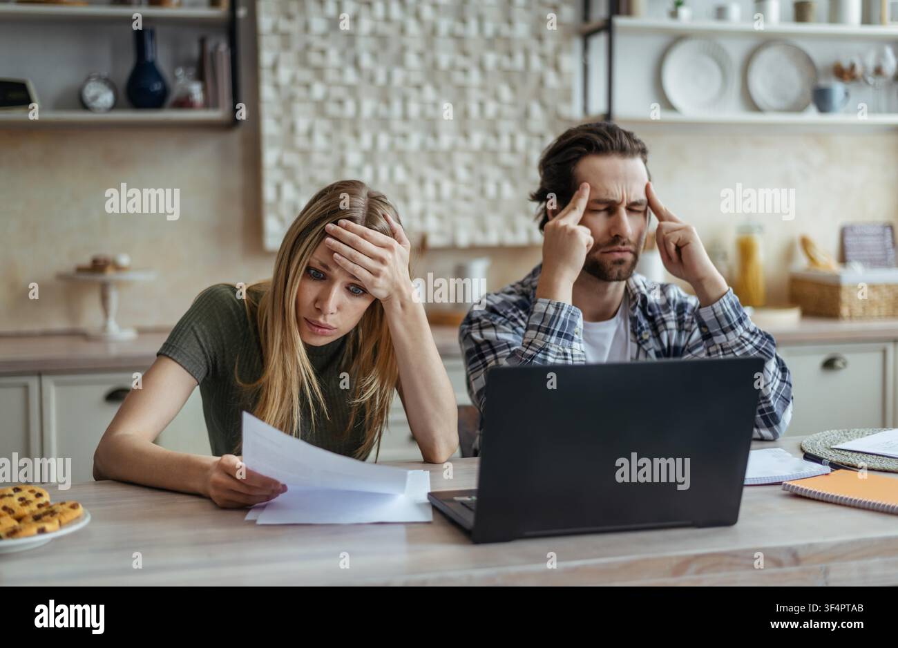 Coppia caucasica preoccupata che esamina documenti finanziari a casa, situazione stressante Foto Stock