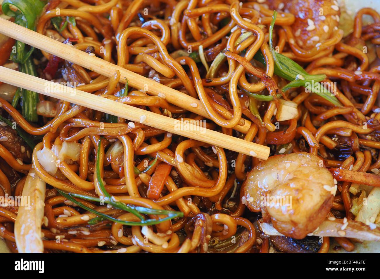 Spaghetti ai gamberetti con bacchette in una ciotola sul tavolo Foto Stock
