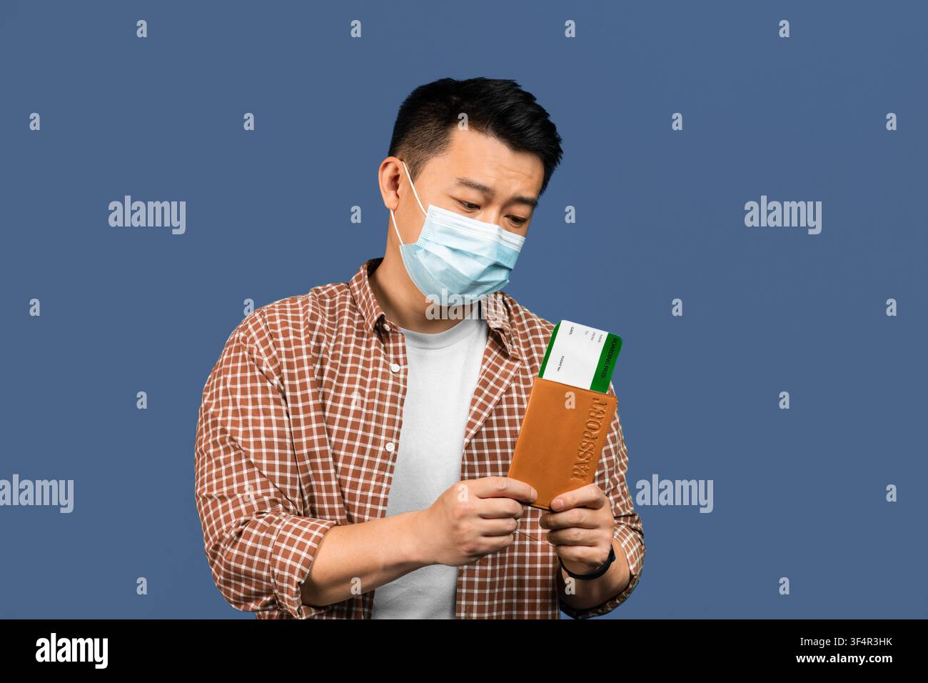 Uomo asiatico con mascherina che controlla documenti e biglietti a casa, concetto di assistenza sanitaria Foto Stock