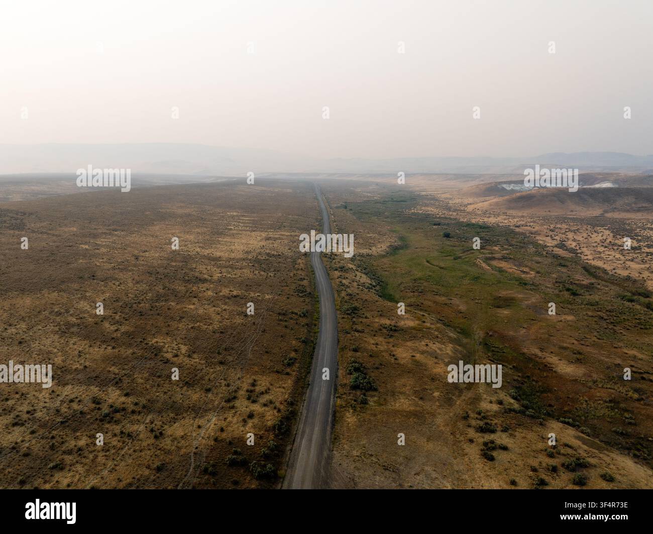 Un piano dall'alto rivela una strada stretta che attraversa vaste pianure Foto Stock