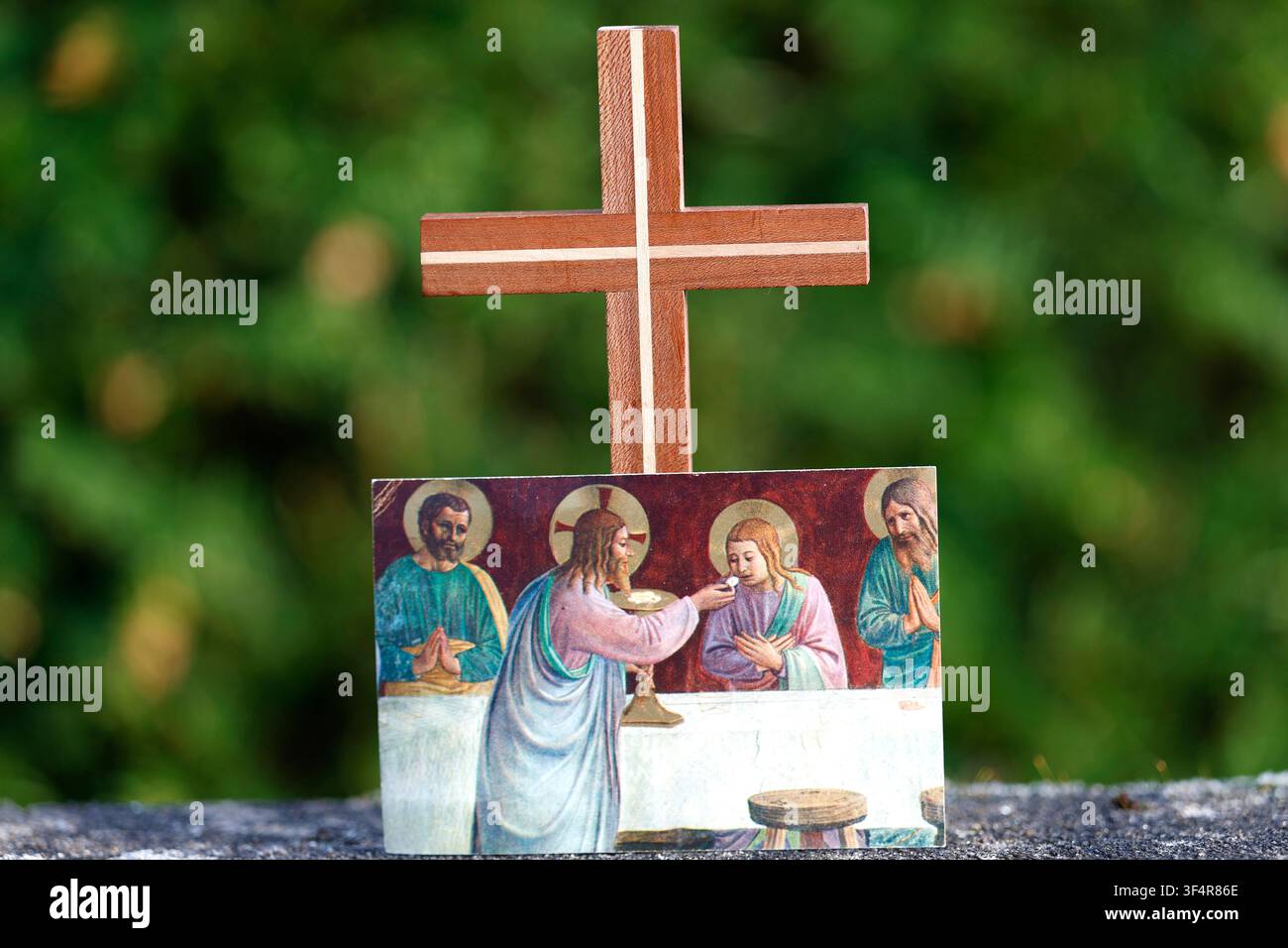 Una natura morta religiosa con una croce fatta a mano e un'immagine religiosa che raffigura Gesù mentre distribuisce l'Eucaristia. Foto Stock