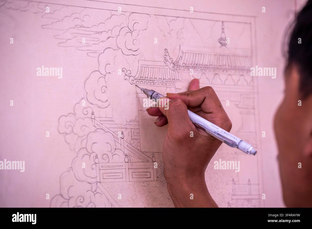 Istituto Norbulingka, Sidhpur, Himachal Pradesh, India. Un artista sta disegnando a mano uno schizzo dettagliato dell'architettura asiatica tradizionale con nuvole. Th Foto Stock