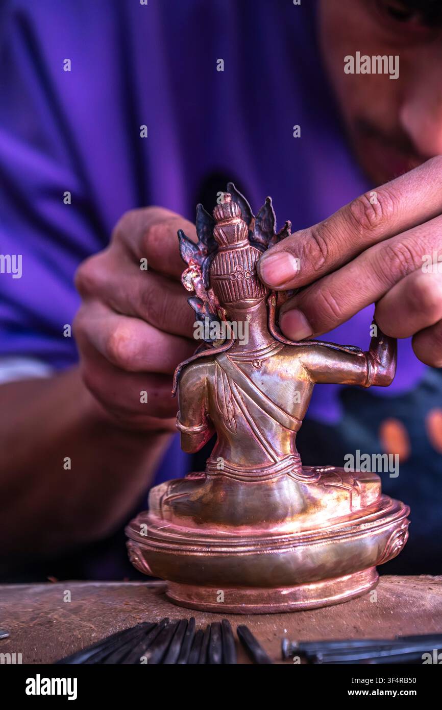 Istituto Norbulingka, Sidhpur, Himachal Pradesh, India. Un artigiano sta lavorando su una statua in metallo che raffigura una figura seduta. Il pezzo è ancora nella Foto Stock