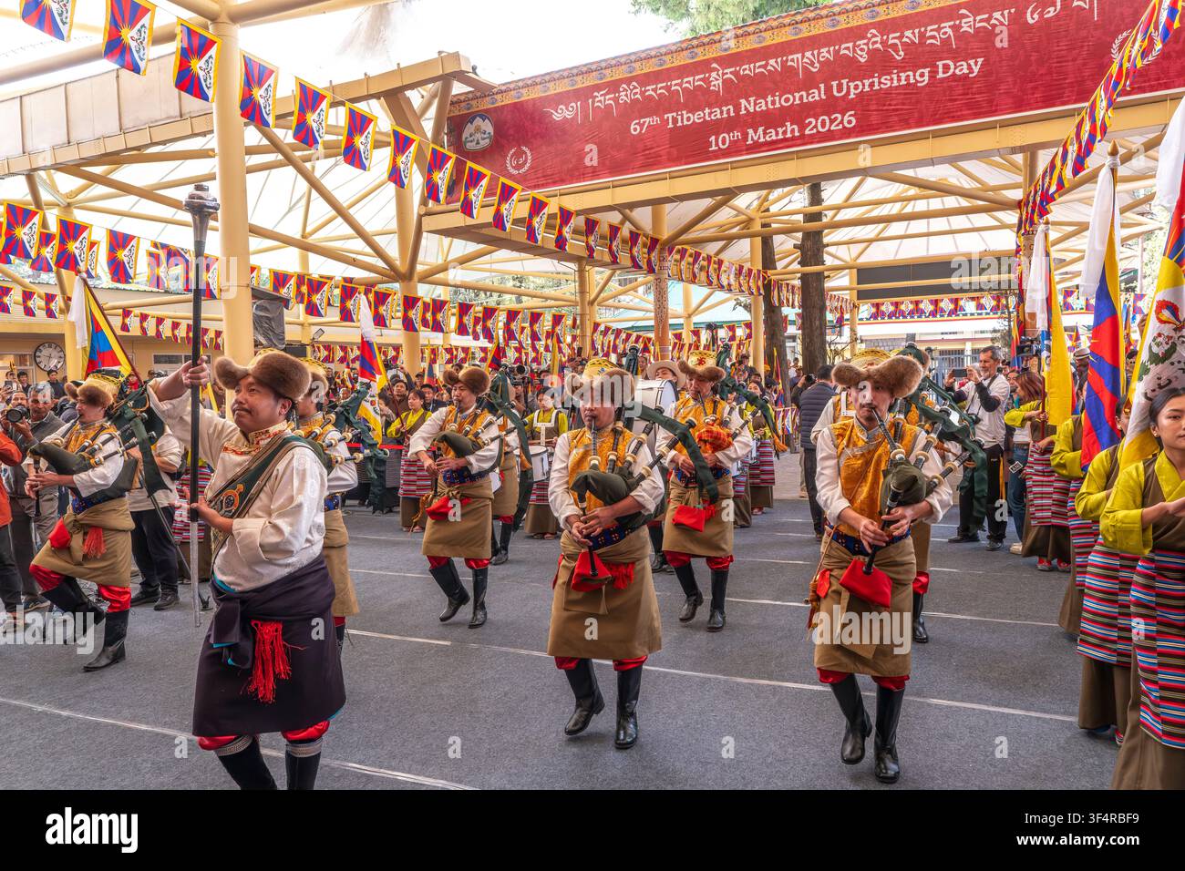 Musici che suonano cornamuse sfilano durante il 67° Giorno della rivolta nazionale tibetana a Dharamsala, in India, il 10 marzo 2026. Foto Stock