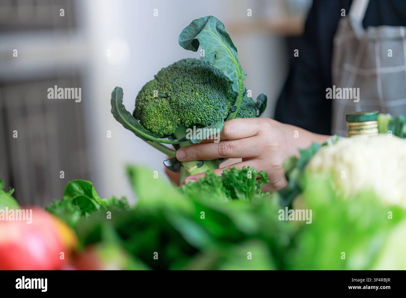 Primo piano di mani che selezionano verdure verdi fresche in una cucina domestica. Concetto di invecchiamento sano, consapevolezza nutrizionale, scelta consapevole del cibo e prevenzione Foto Stock