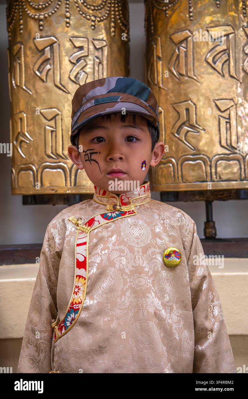 Un bambino indossa abiti tradizionali e un cappello camuffato durante la Giornata della Rivolta Nazionale Tibetana a Dharamsala, Himachal Pradesh, India. Foto Stock