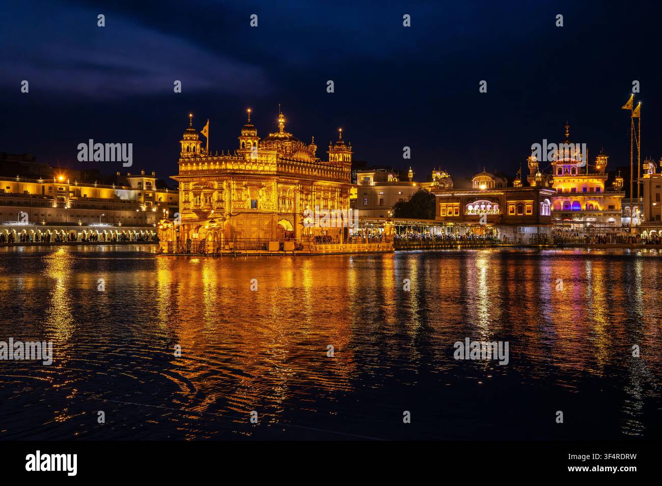 Il magnifico Tempio d'Oro, un sito sacro sikh ad Amritsar, in India, brilla brillantemente di notte, i suoi riflessi dorati sull'acqua creano una u Foto Stock
