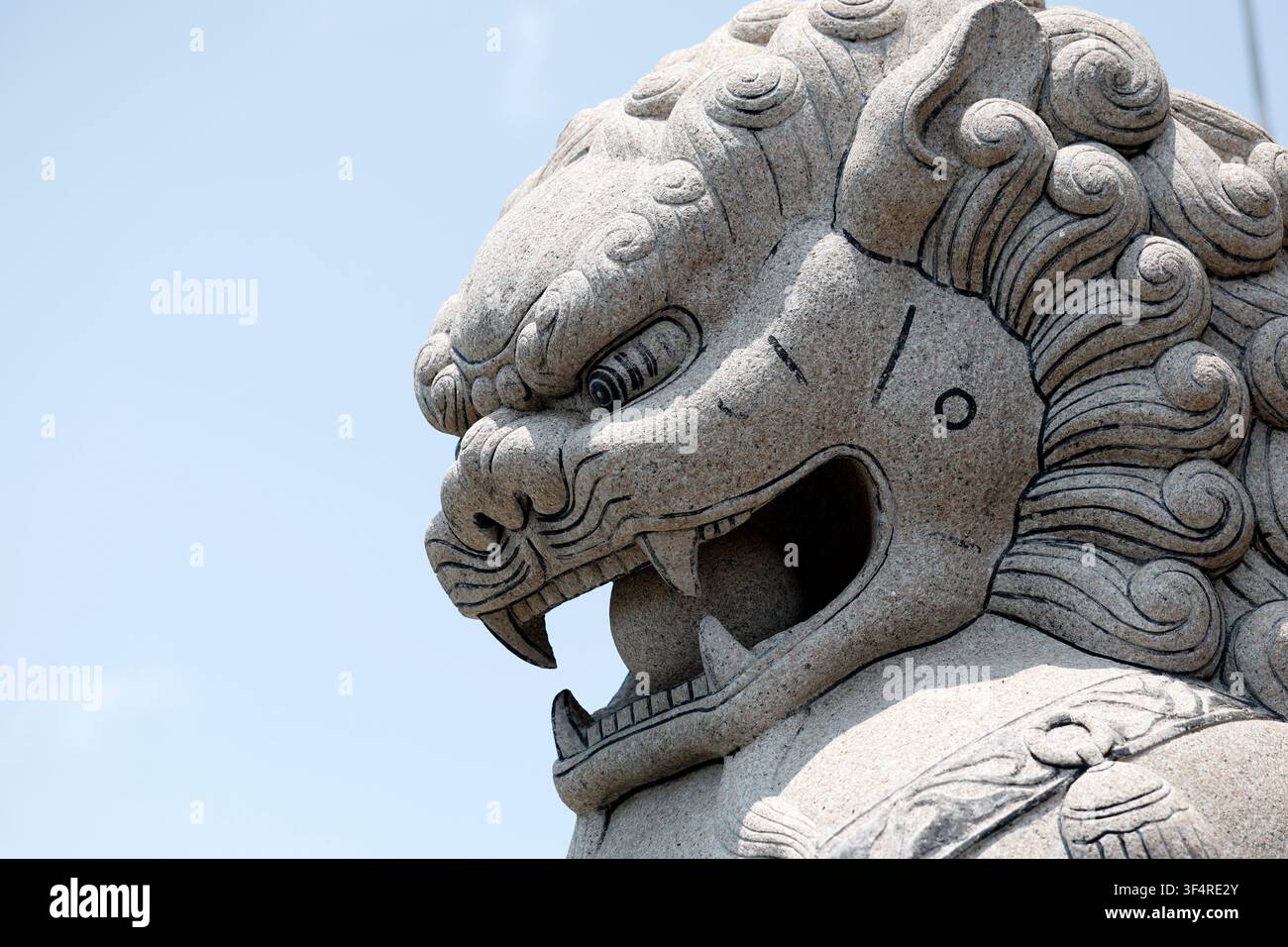 Tempio cinese Viharn Sien. Una scultura di leone guardiano in pietra, con criniera dettagliata e bocca aperta. Pattaya, Thailandia. Foto Stock