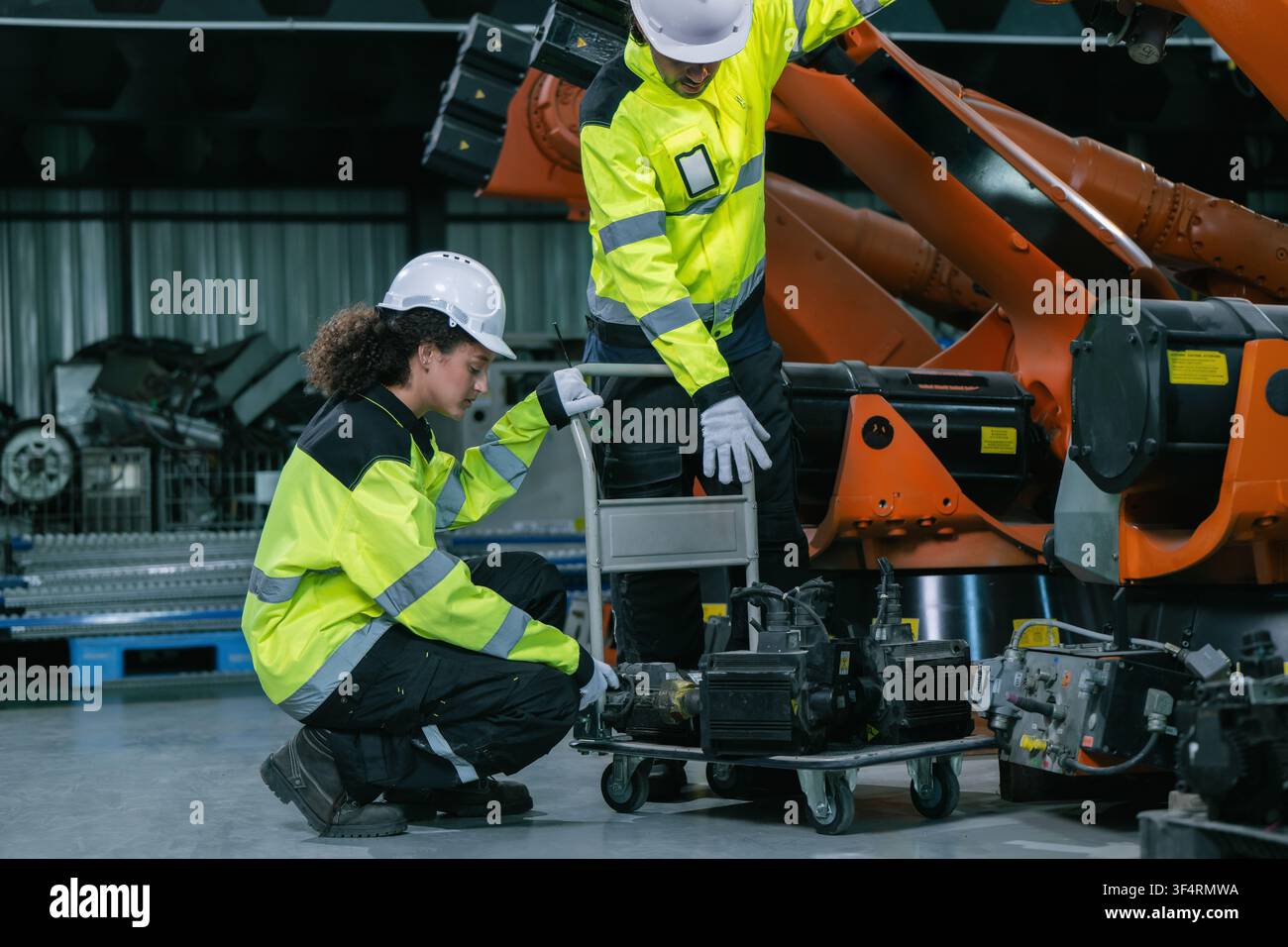 Team di ingegneri industriali che controlla un servomotore per la manutenzione di un braccio robotico in magazzino. Concetto di servizio di manutenzione di macchinari industriali pesanti, eq Foto Stock
