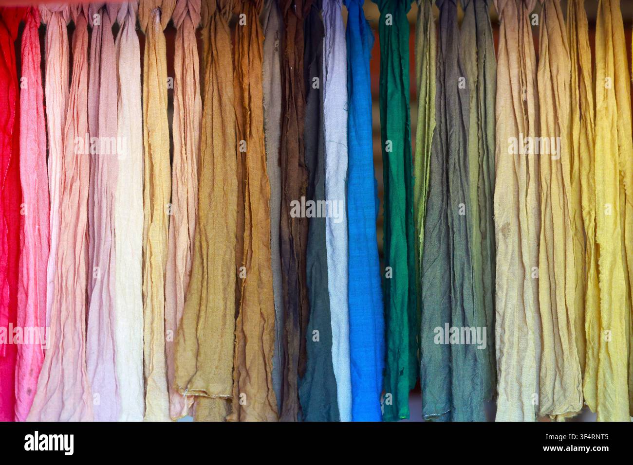 Una varietà di tessuti in colori naturali, tinti con materiali vegetali, è in mostra nelle botteghe del cantiere medievale di Guédelon Foto Stock
