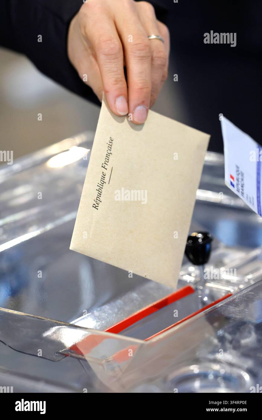 Una mano inserisce una scheda ufficiale della Repubblica francese in un'urna elettorale. Elezione. Foto Stock