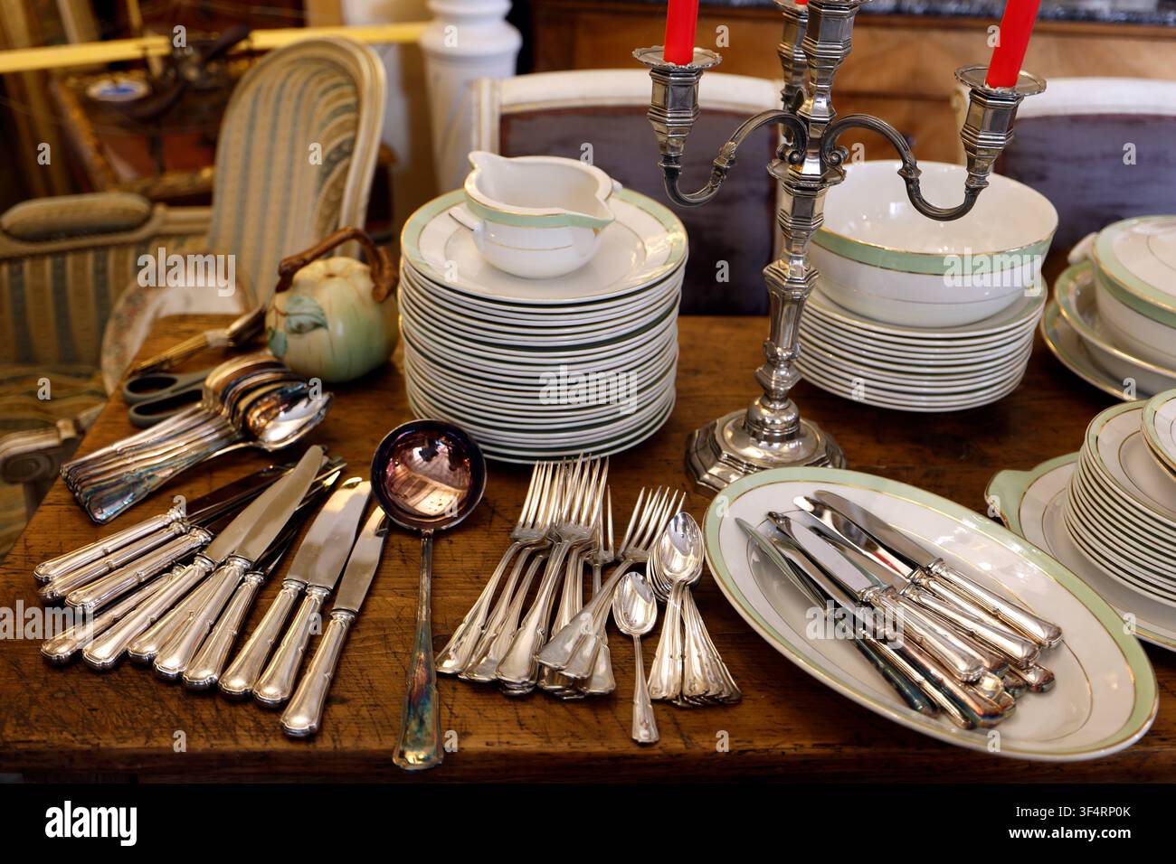 Commerciante di antiquariato. Tavolo antico, posate d'argento, candelabri e raffinata porcellana da tavola. Foto Stock