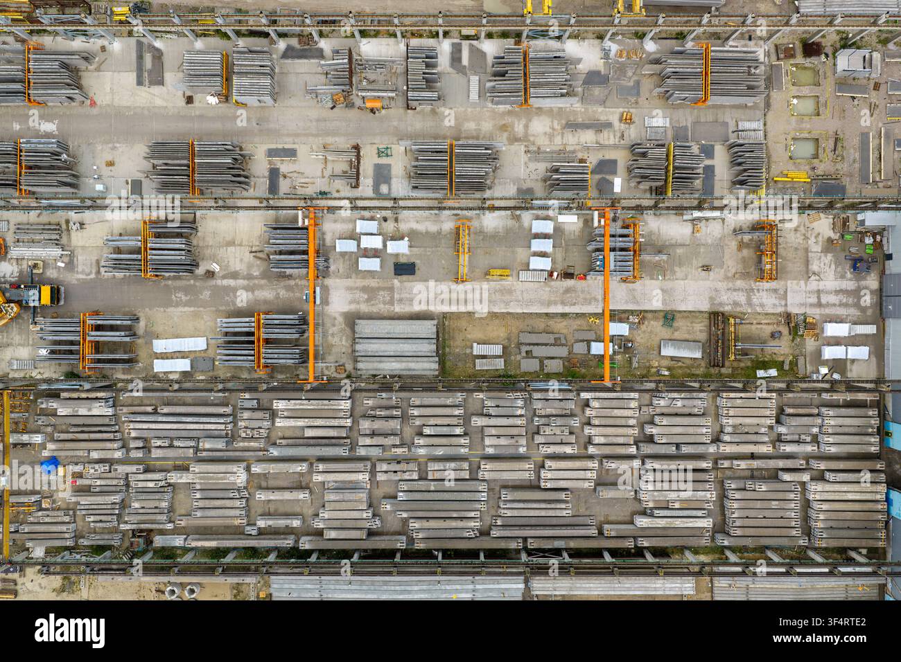 Vista aerea di un cantiere di produzione di elementi in cemento precompresso con file di travi impilate, gru industriali sospese e aree di stoccaggio organizzate a Po Foto Stock