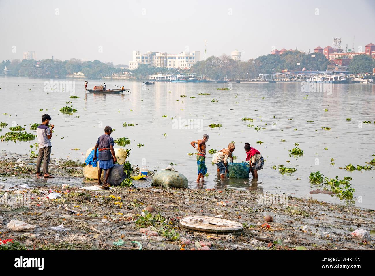 Le persone stanno lavorando sulle rive inquinate del fiume Hoogly a Kolkata, nel Bengala Occidentale, India. Foto Stock