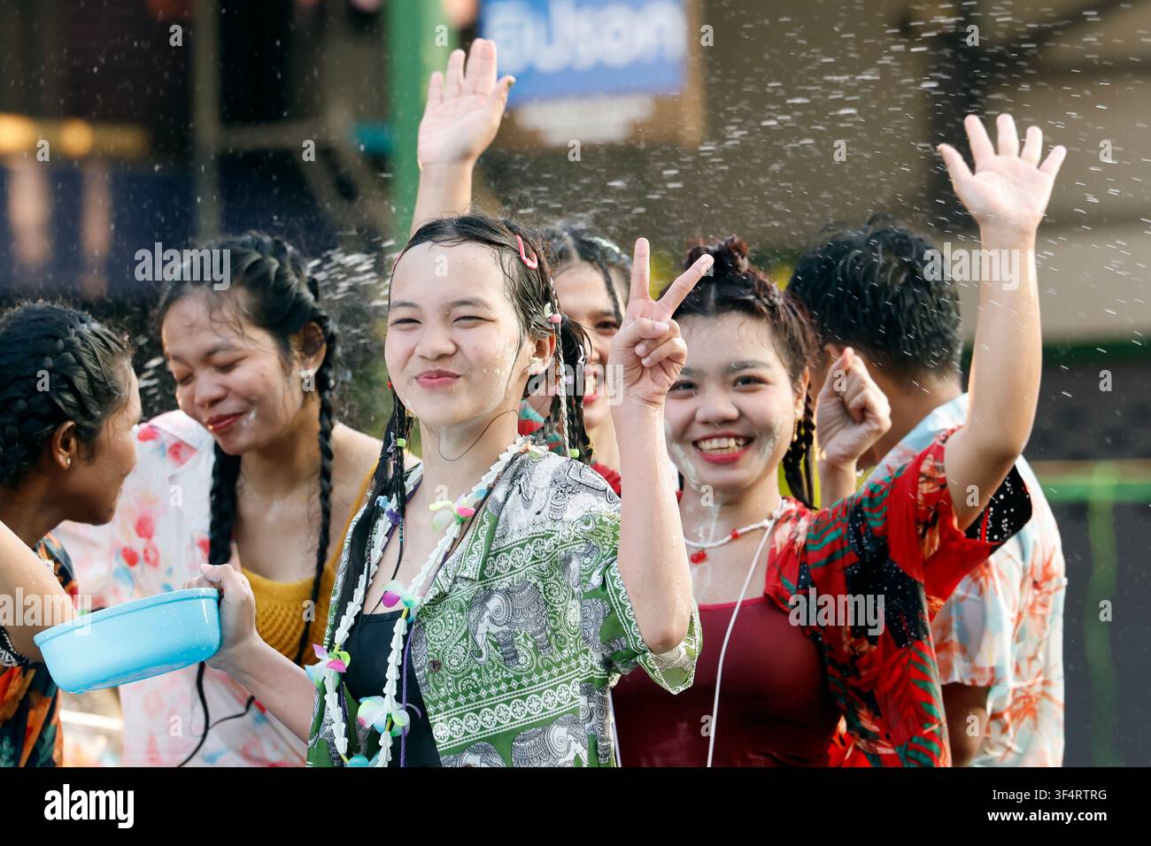 Giovani donne celebrano con gioia il Songkran, il Capodanno thailandese, con schizzi d'acqua e sorrisi raggiunti, segnando una tradizione culturale di rinnovamento e sha Foto Stock