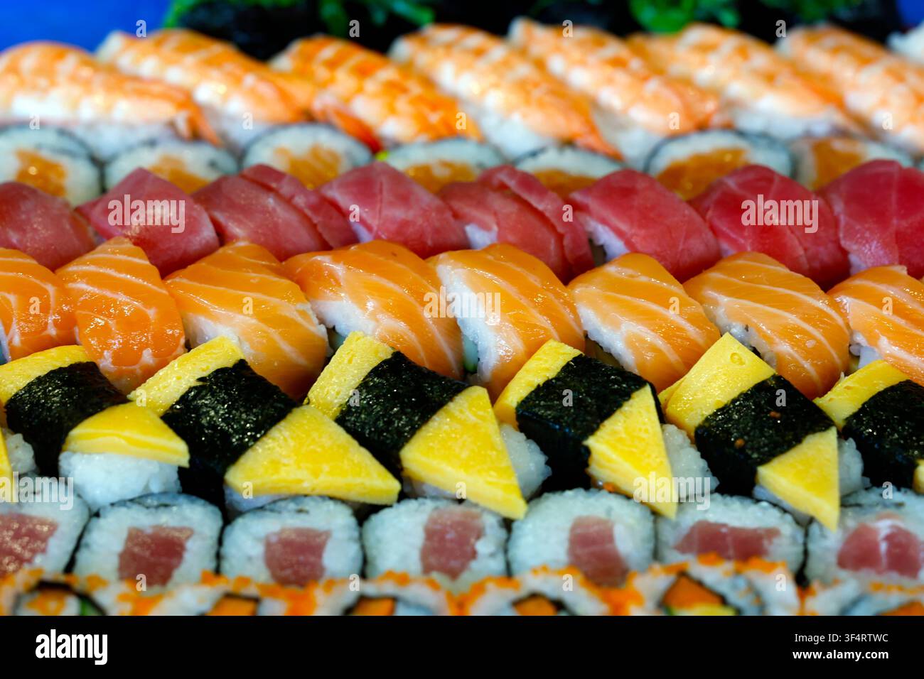 Una varietà colorata di sushi e maki, con salmone, tonno, gamberetti e tamagoyaki Foto Stock