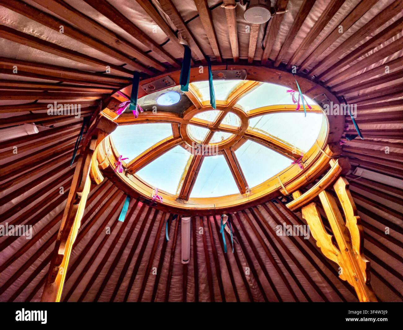 Guarda verso l'alto dall'interno di una yurta attraverso l'apertura circolare, le travi di legno creano un motivo strutturato contro il cielo. Foto Stock
