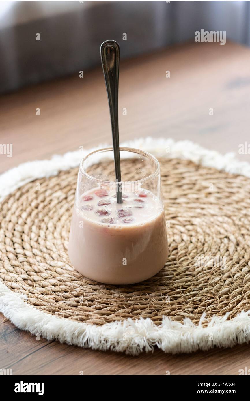 Caffè Bumble con succo di ciliegia ghiacciato in un bicchiere trasparente su un tavolo di legno. Bevanda estiva rinfrescante servita su un tessuto naturale Foto Stock