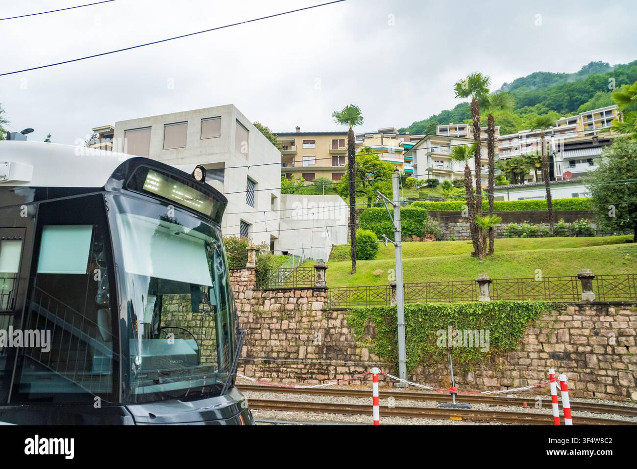 Caslano - Svizzera - 12 maggio 2026: Cabina anteriore del treno con vista sul villaggio collinare Foto Stock
