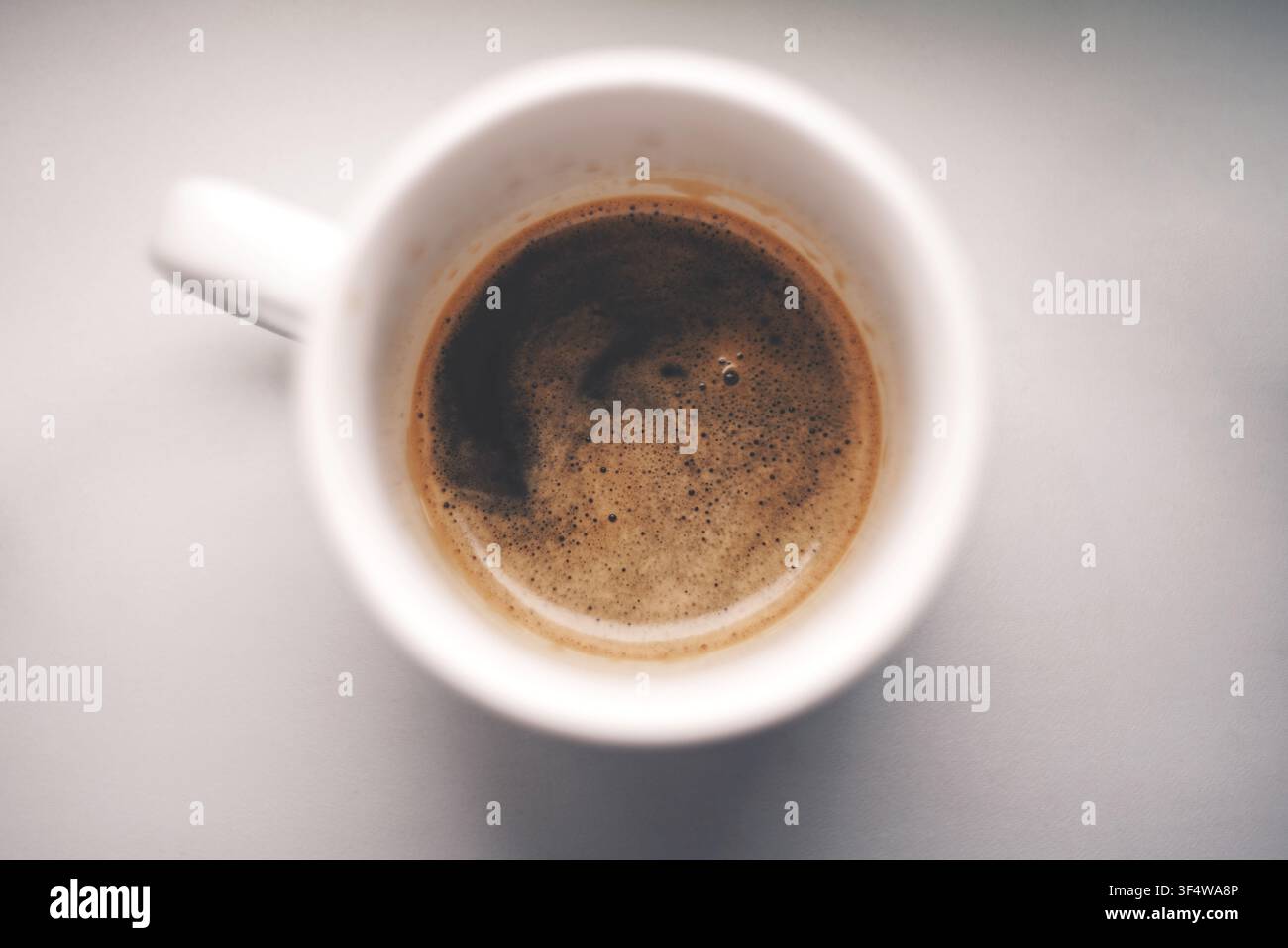 Una bevanda caffè appena preparata con schiuma ricca in una tazza di ceramica bianca, vista dall'alto. Foto Stock