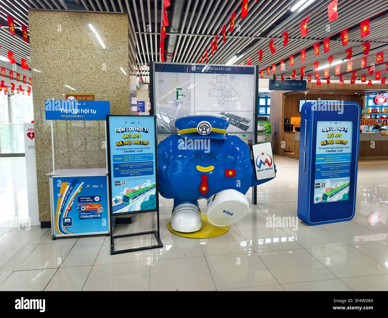 Mascotte blu in cartone animato per il sistema Hanoi Metro in una mostra promozionale per un sistema di biglietteria biometrica automatizzato, stazione di Cat Linh, Hanoi, Vietnam Foto Stock