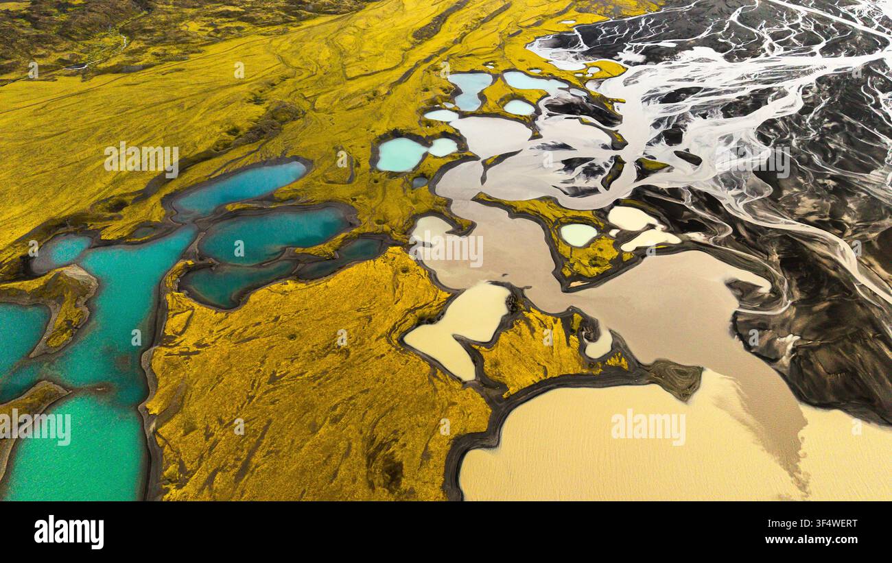 Vista aerea di bacini di acqua di fusione turchese e canali glaciali intrecciati tra muschio e sabbia vulcanica nera a est del ghiacciaio Mýrdalsjökull, in Islanda. Foto Stock