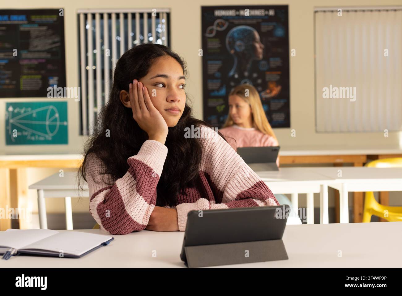 Adolescenti femminili diverse in classe, a sinistra un'adolescente con maglia a righe guarda a destra usando un tablet-taccuino Foto Stock