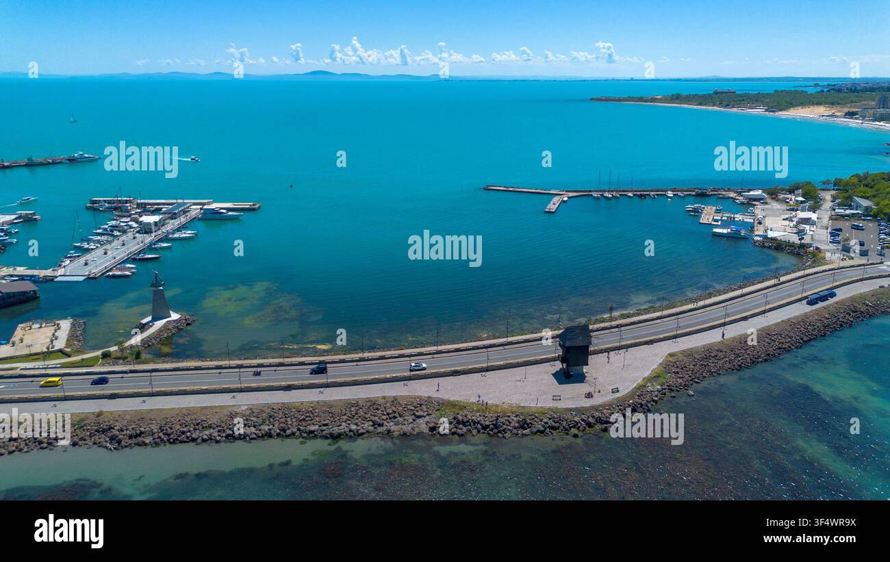 Vista aerea panoramica della storica strada rialzata con l'iconico mulino a vento in legno e il porticciolo turistico all'ingresso del sito UNESCO di Nesebar in Bulgaria Foto Stock