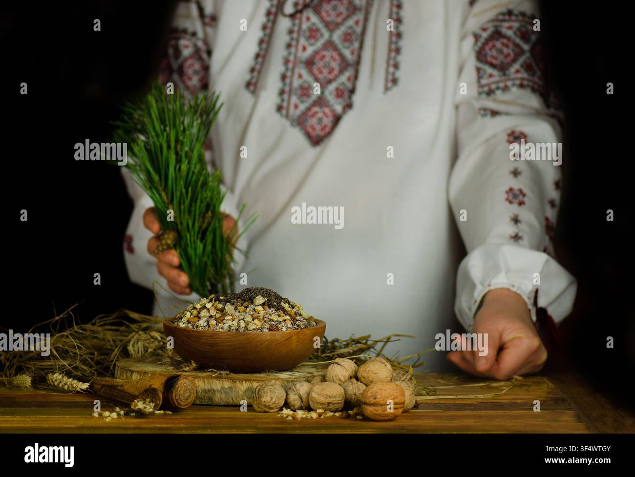 Donna in abito nazionale ucraino sta preparando una cena natalizia festosa. Donna in abito ricamato che prepara la kutia ucraina tradizionale. Donna in Foto Stock