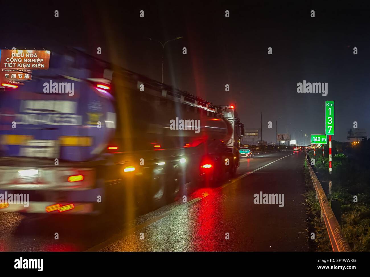 Un camion su un'autostrada notturna diretto ad Hanoi, Vietnam. Indicatore verde verticale che mostra il segnaposto "Km 137" Foto Stock