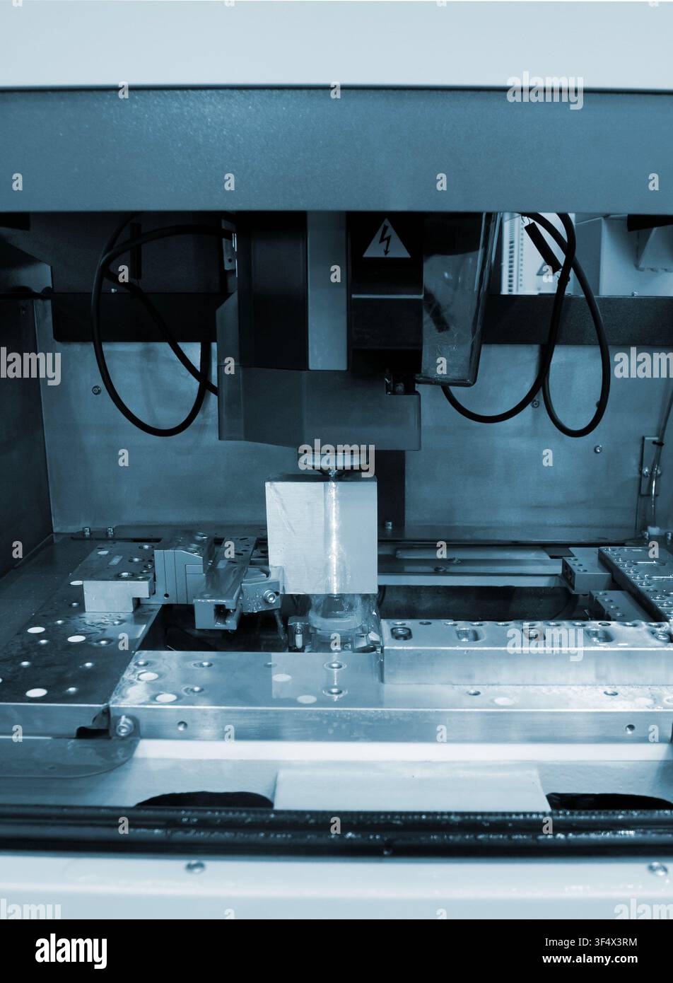 Lavorazione a scarica elettrica. Lavorazione a scarica elettrica a filo EDM su macchina CNC. Macchina che taglia il metallo con un filo contenente scariche elettriche in dielettrico liquido. processo ad alta precisione Foto Stock