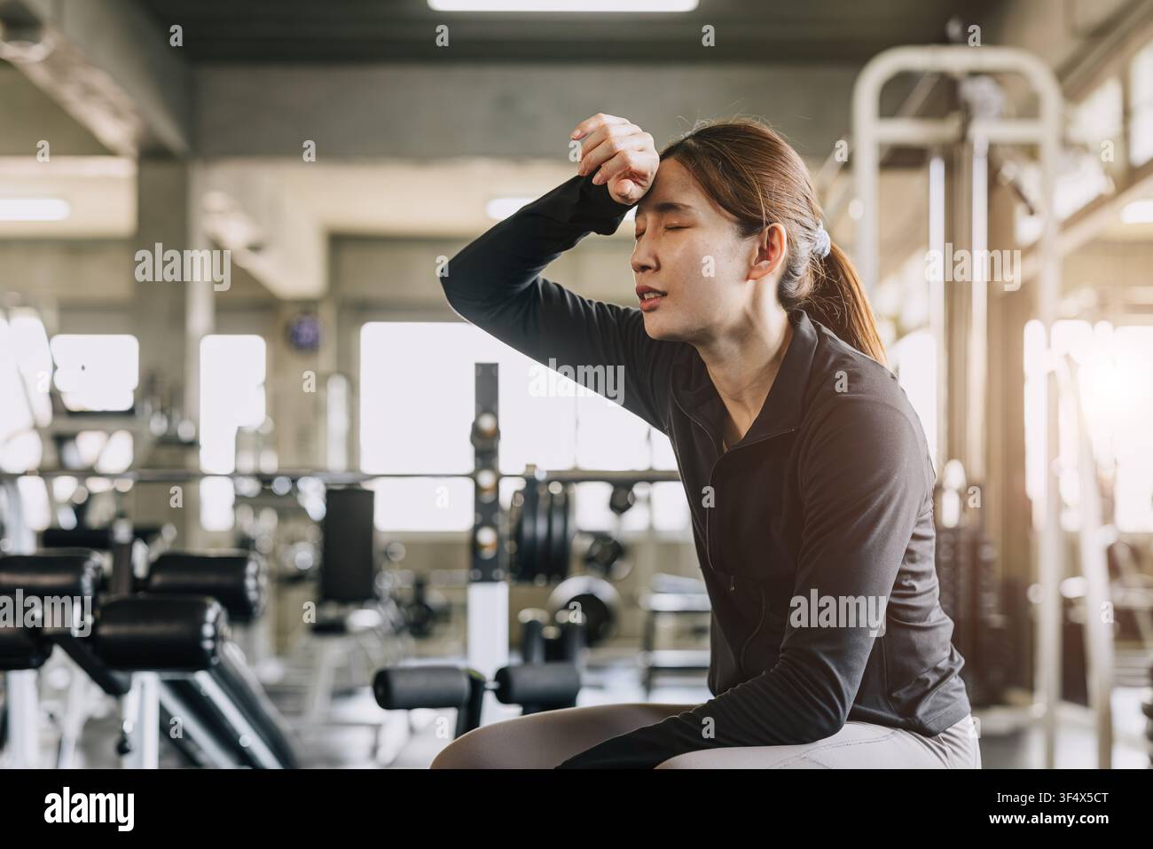 Donna sportiva stanca esausta affaticata sudando in palestra per l’impatto di un’ondata di caldo condizioni calde scarso ricambio d’aria o attività intensa Foto Stock