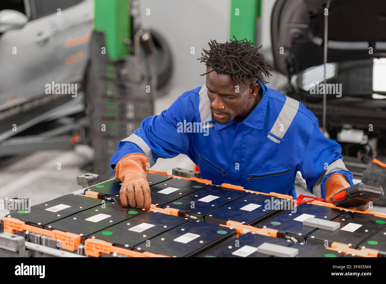 Servizio professionale per auto elettriche, lavoratore maschile, manutenzione di veicoli elettrici, riparazione della batteria nell'officina garage EV. Foto Stock