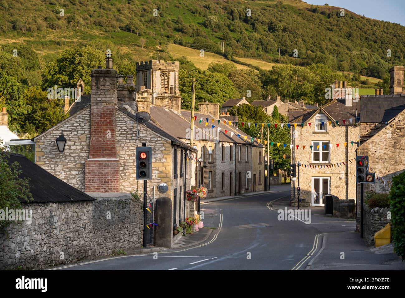 Bandiere festive si estendono su una strada scenografica con cottage in pietra e semafori nel centro del villaggio di Bradwell, Peak District, Inghilterra Foto Stock