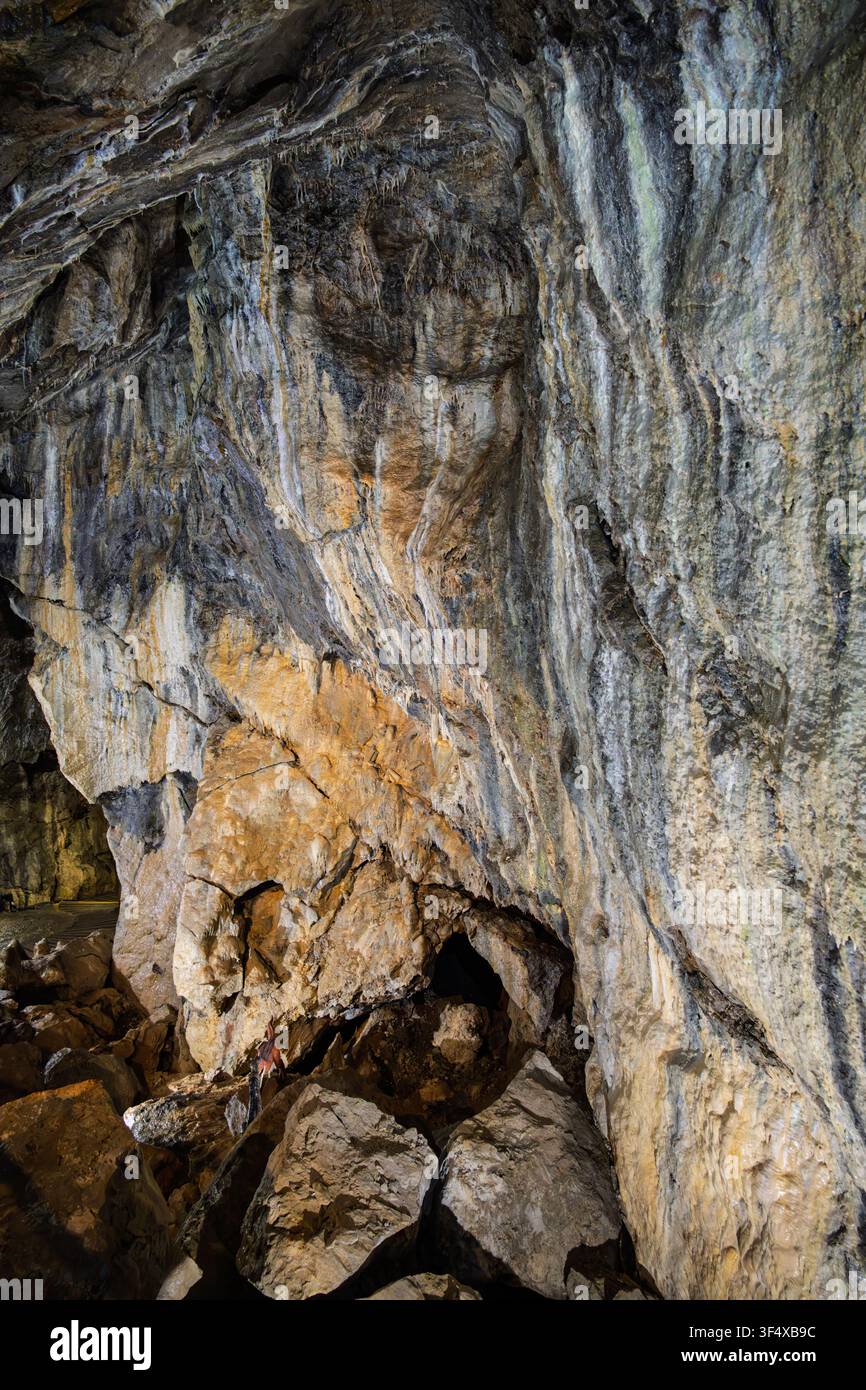 La spettacolare formazione di cascata ghiacciata a forma di colata si riversa lungo un imponente muro di roccia calcareo illuminato all'interno della storica grotta di Treak Cliff Foto Stock