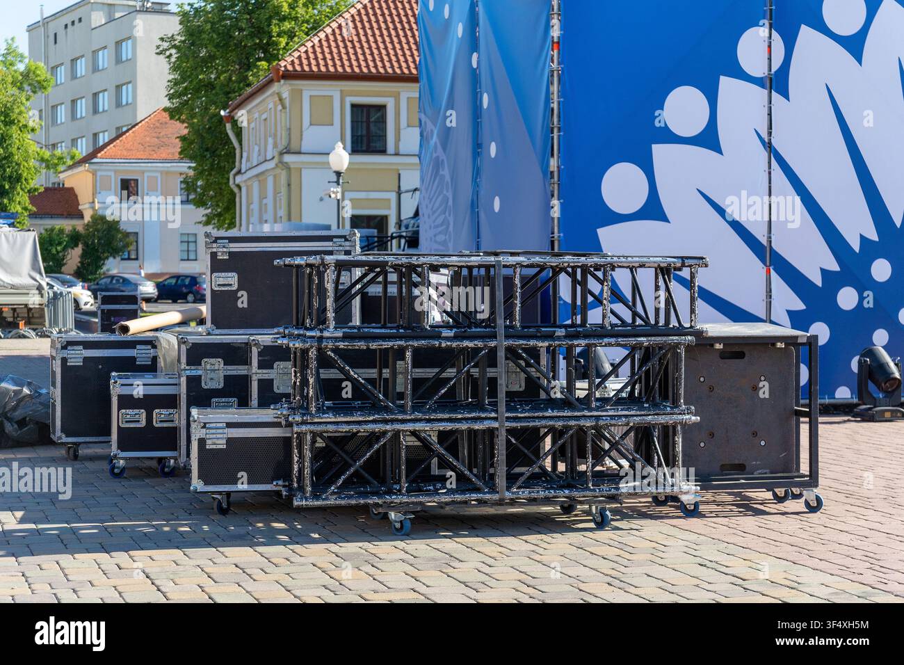 Truss metallico per palcoscenici e valigie di trasporto nere allestiti su una piazza di ciottoli per un concerto all'aperto o la preparazione di un evento. Foto Stock
